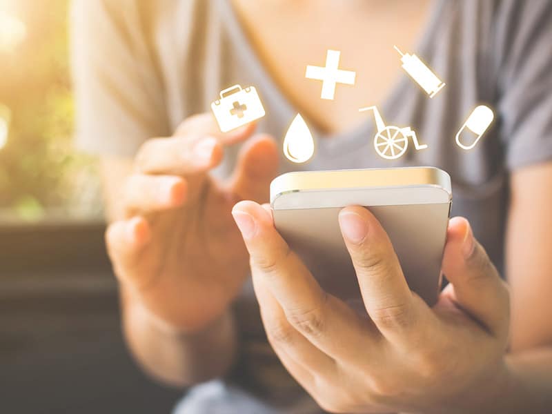 A person accessing healthcare information from her phone symbolizing patient engagement with a medical team.