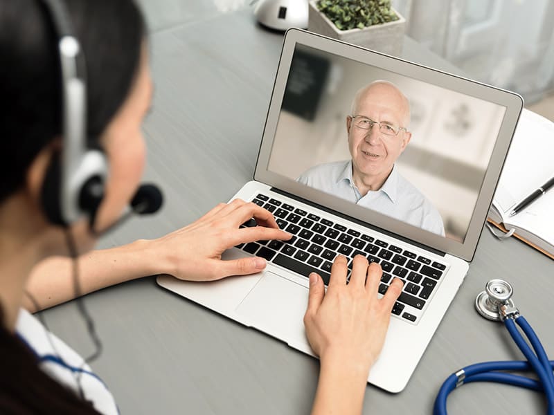 Doctor talking with a senior patient about his Annual Wellness Visit via telehealth.