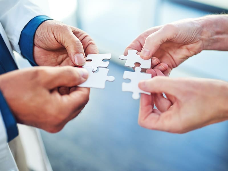 Two physicians putting puzzle pieces together symbolizing care coordination.